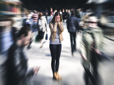 Woman covering her face in the middle of a blurred crowd