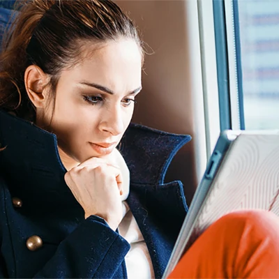 Woman sitting on train looking at tablet