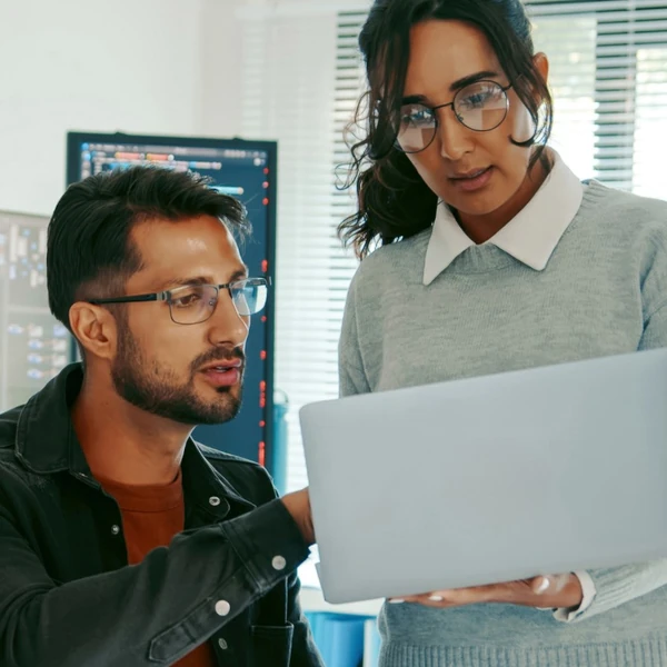 Woman showing man something on a laptop
