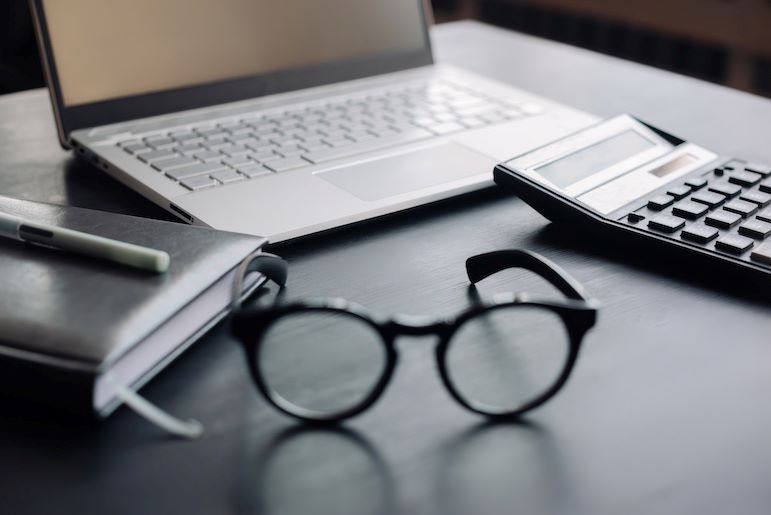 accounting professional's glasses next to laptop and calculator