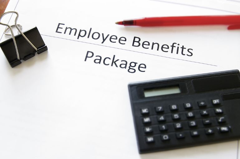 Employee benefits package document with pen, calculator, and binder clip