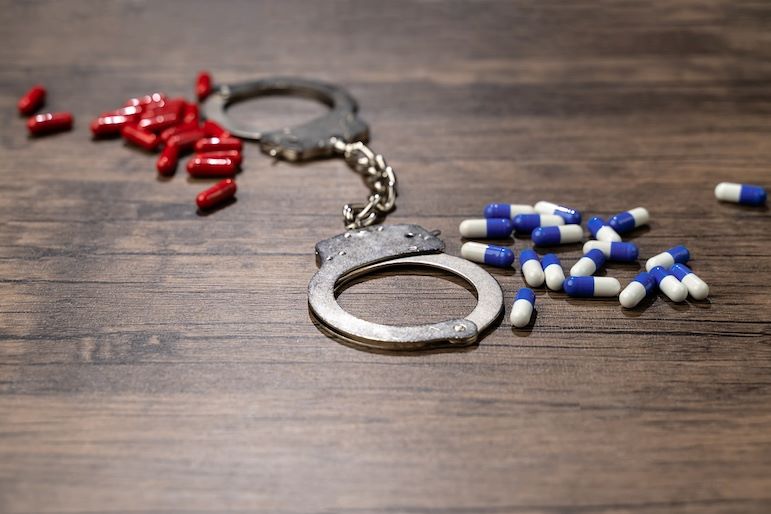 DEA Agent's handcuffs near narcotics