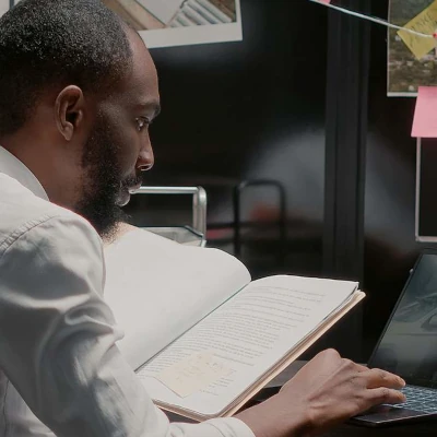 Man looking at notes and typing on computer